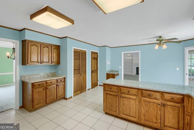 1197 Kenilworth Trce, Snellville, GA 30078 - kitchen with ceiling fan, brown cabinets, ornamental molding, light stone countertops, and light tile patterned floors