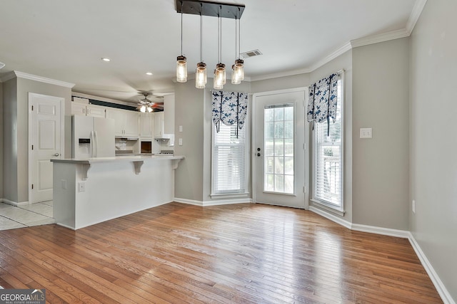 77 Springfield Ct, Newnan, GA 30265 - kitchen with white fridge with ice dispenser, light wood-style floors, ceiling fan, crown molding, and a peninsula