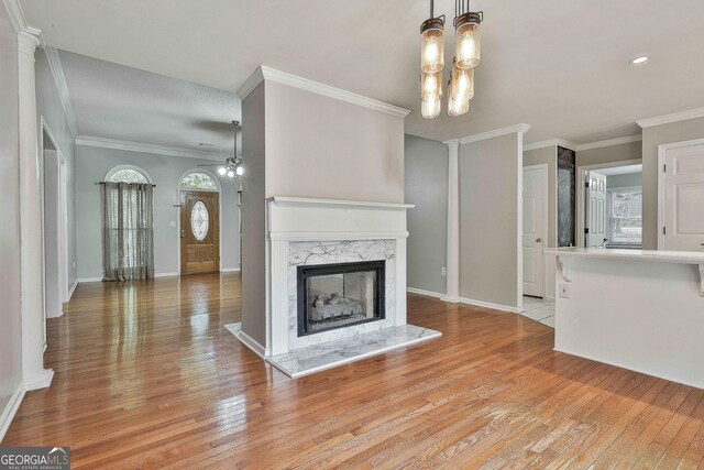 77 Springfield Ct, Newnan, GA 30265 - unfurnished living room featuring light wood-style floors, a fireplace, ornamental molding, ceiling fan, and healthy amount of natural light