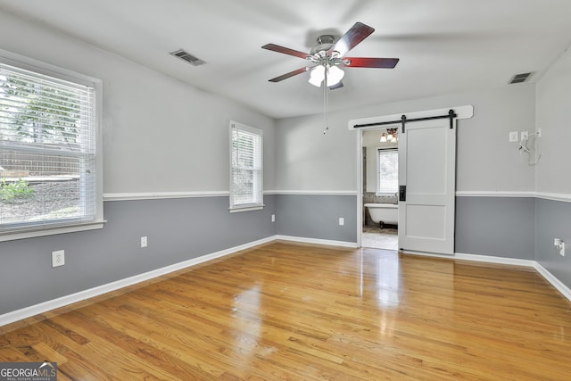 77 Springfield Ct, Newnan, GA 30265 - empty room featuring plenty of natural light, ceiling fan, a barn door, and light wood-type flooring