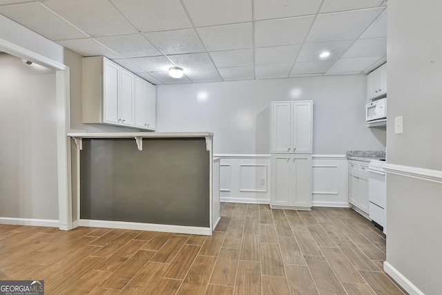 77 Springfield Ct, Newnan, GA 30265 - kitchen with white appliances, light wood-style flooring, a peninsula, light countertops, and a drop ceiling