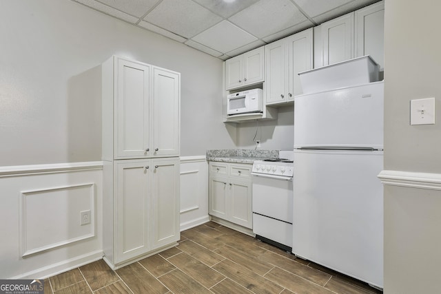 77 Springfield Ct, Newnan, GA 30265 - kitchen featuring white appliances, dark wood-style flooring, light countertops, a wainscoted wall, and white cabinetry