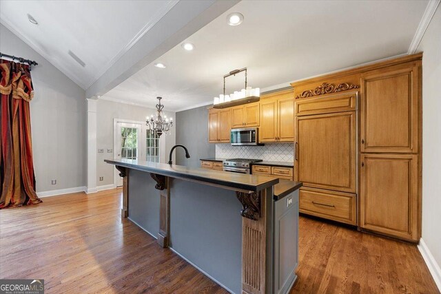 133 N Wellington, Macon, GA 31210 - kitchen with appliances with stainless steel finishes, wood finished floors, a kitchen island with sink, dark countertops, and decorative backsplash