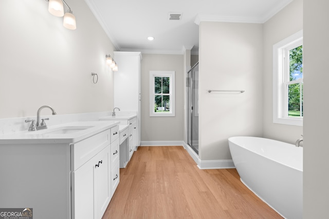 19 Honeysuckle Dr, Claxton, GA 30417 - full bathroom featuring wood finished floors, double vanity, a freestanding bath, crown molding, and a stall shower