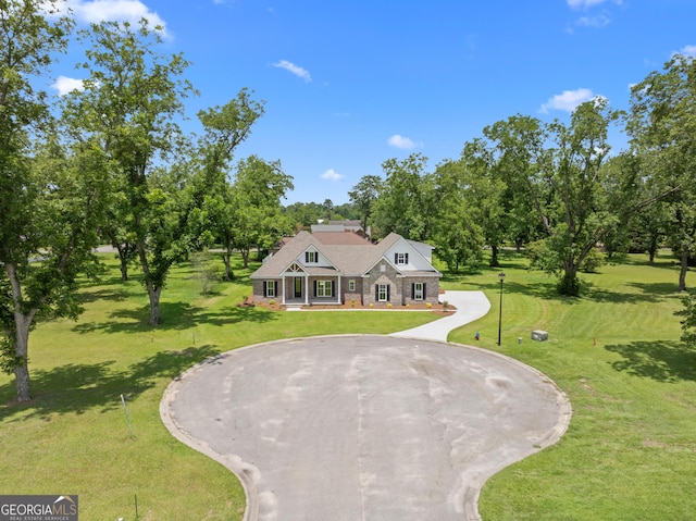 19 Honeysuckle Dr, Claxton, GA 30417 - view of front of property with curved driveway, stone siding, a front lawn, and covered porch