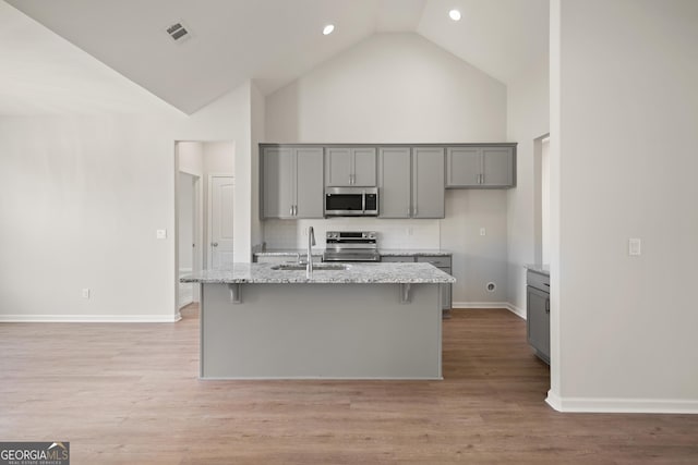 109 Wave Break Ct, Kingsland, GA 31548 - kitchen featuring stainless steel appliances, gray cabinets, high vaulted ceiling, light stone countertops, and decorative backsplash