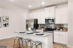 42 Buckingham Ln Unit 233, Hoschton, GA 30548 - kitchen featuring stainless steel appliances, a breakfast bar area, white cabinets, a kitchen island with sink, and recessed lighting
