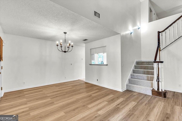 116 Overlook Bnd, Kingsland, GA 31548 - unfurnished living room with wood finished floors, stairs, a chandelier, and a textured ceiling
