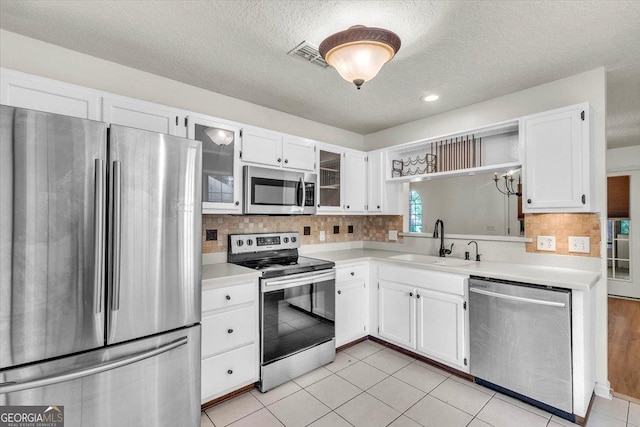 116 Overlook Bnd, Kingsland, GA 31548 - kitchen featuring appliances with stainless steel finishes, light countertops, a textured ceiling, white cabinets, and glass insert cabinets