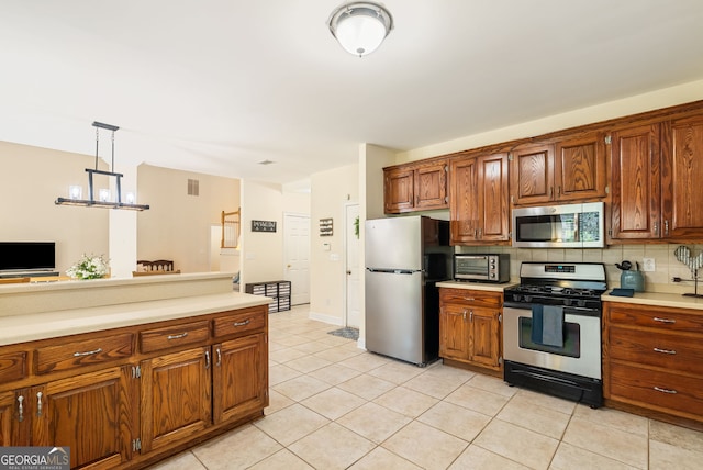 595 Mcgarity Dr, Mcdonough, GA 30252 - kitchen with stainless steel appliances, decorative backsplash, light tile patterned floors, light countertops, and brown cabinetry