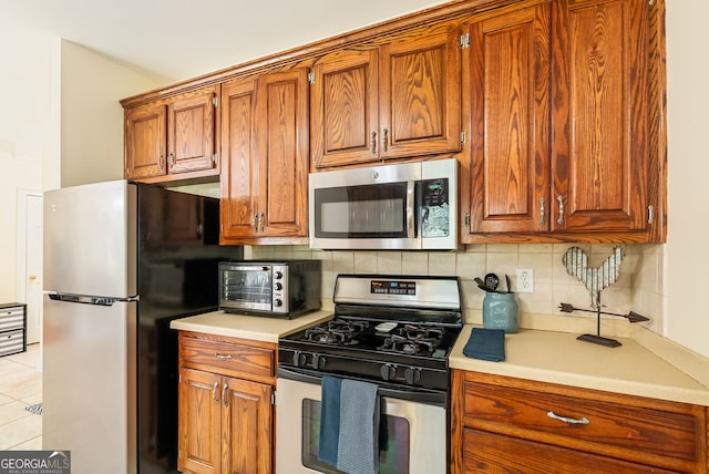 595 Mcgarity Dr, Mcdonough, GA 30252 - kitchen featuring appliances with stainless steel finishes, backsplash, brown cabinetry, and light countertops