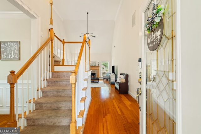 595 Mcgarity Dr, Mcdonough, GA 30252 - foyer entrance with wood finished floors, a ceiling fan, stairway, a high ceiling, and a warm lit fireplace