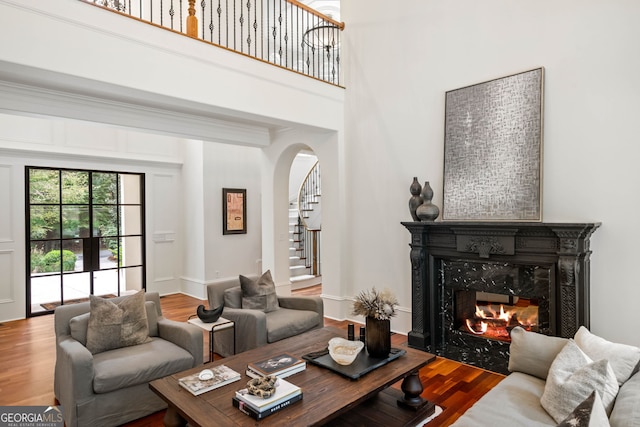 3401 Stillhouse Rd SE, Atlanta, GA 30339 - living room with arched walkways, stairs, wood finished floors, a premium fireplace, and a towering ceiling
