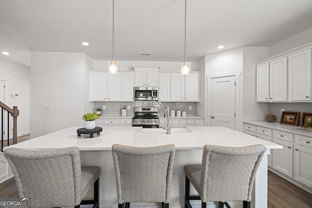 1313 Pj E Rd, Covington, GA 30014 - kitchen featuring appliances with stainless steel finishes, dark wood finished floors, backsplash, recessed lighting, and an island with sink