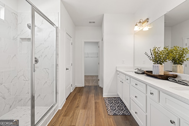 1313 Pj E Rd, Covington, GA 30014 - bathroom with double vanity, a shower stall, wood finished floors, and a walk in closet
