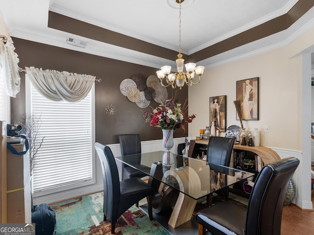 141 Wexford Ct, Stockbridge, GA 30281 - dining area with a chandelier, a raised ceiling, a wainscoted wall, ornamental molding, and wood finished floors
