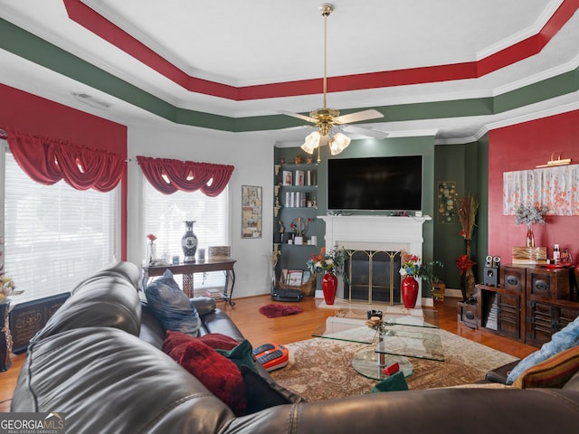 141 Wexford Ct, Stockbridge, GA 30281 - living area with wood finished floors, ornamental molding, a ceiling fan, a fireplace with flush hearth, and a tray ceiling