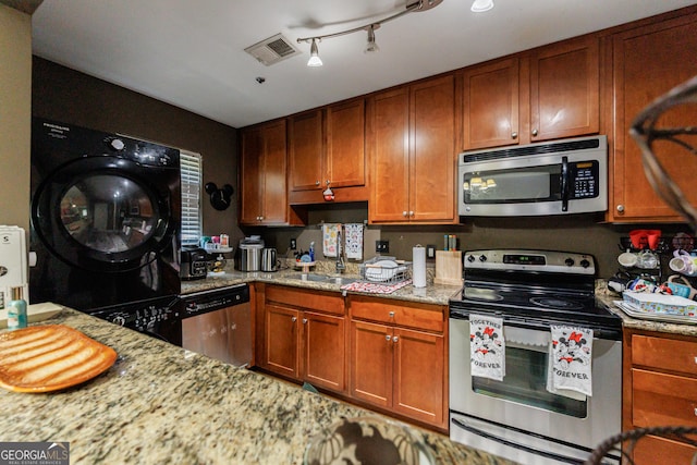 105 N River Dr Unit G, Sandy Springs, GA 30350 - kitchen featuring appliances with stainless steel finishes, washer / dryer, light stone countertops, and brown cabinetry