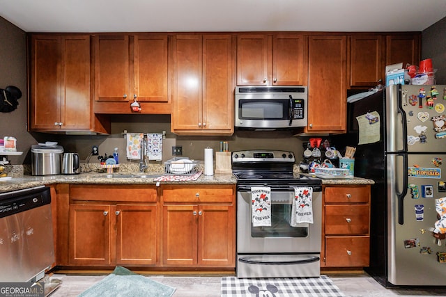 105 N River Dr Unit G, Sandy Springs, GA 30350 - kitchen featuring appliances with stainless steel finishes, light stone counters, and brown cabinetry