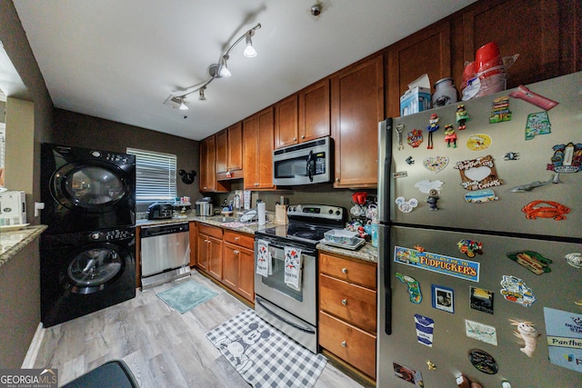105 N River Dr Unit G, Sandy Springs, GA 30350 - kitchen featuring stainless steel appliances, estacked washer and dryer, light wood-style floors, brown cabinetry, and light stone counters