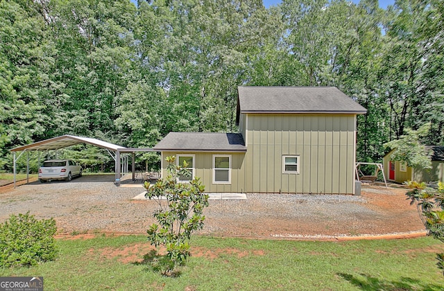 460 Morgan Mill Rd, Brooks, GA 30205 - view of front facade featuring gravel driveway, a shingled roof, board and batten siding, a carport, and a storage unit