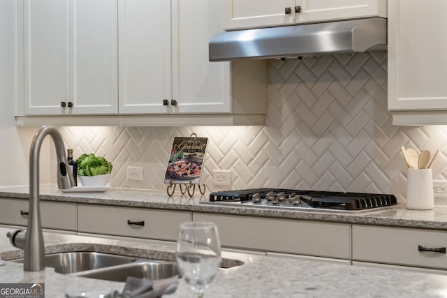 10580 Grandview Sq, Johns Creek, GA 30097 - kitchen featuring under cabinet range hood, stainless steel gas cooktop, white cabinetry, backsplash, and light stone countertops