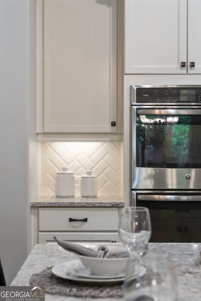10580 Grandview Sq, Johns Creek, GA 30097 - kitchen view of double oven, white cabinets, backsplash, and light stone counters