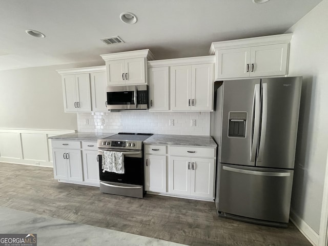113 Sourwood Ln, Warner Robins, GA 31093 - kitchen featuring stainless steel appliances, white cabinetry, dark wood-style flooring, tasteful backsplash, and a wainscoted wall
