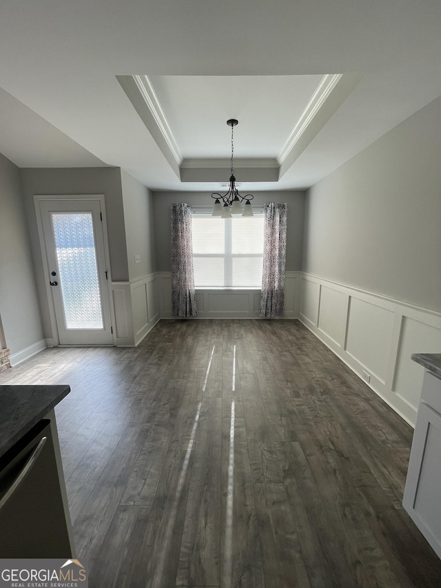113 Sourwood Ln, Warner Robins, GA 31093 - unfurnished dining area with a chandelier, a tray ceiling, dark wood-style flooring, wainscoting, and a decorative wall