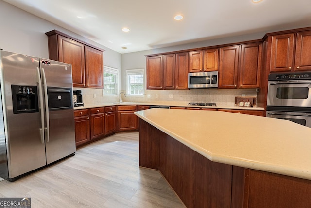 2940 Bentbill Xing, Cumming, GA 30041 - kitchen featuring appliances with stainless steel finishes, light wood-type flooring, recessed lighting, tasteful backsplash, and light countertops