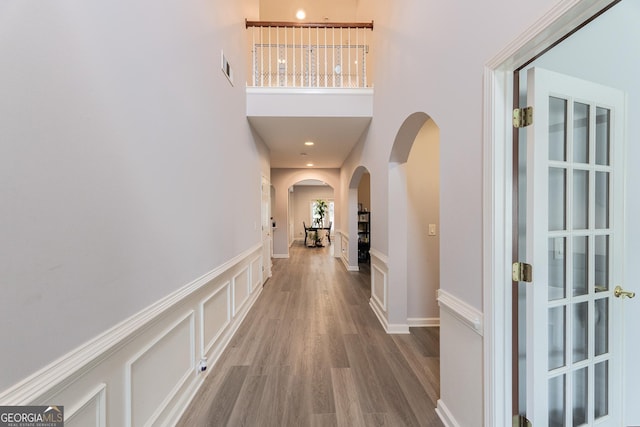 2940 Bentbill Xing, Cumming, GA 30041 - hall featuring arched walkways, wood finished floors, a high ceiling, a wainscoted wall, and a decorative wall