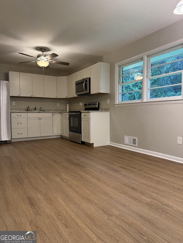 882 Campbell Rd, Covington, GA 30014 - kitchen featuring stainless steel appliances, wood finished floors, white cabinets, and a ceiling fan