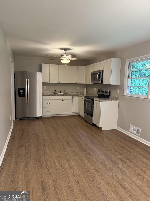 882 Campbell Rd, Covington, GA 30014 - kitchen featuring appliances with stainless steel finishes, white cabinets, dark wood-style flooring, and a ceiling fan