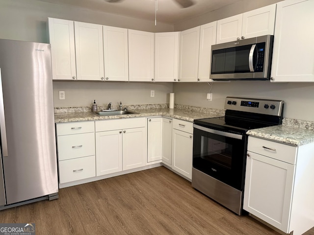 882 Campbell Rd, Covington, GA 30014 - kitchen featuring stainless steel appliances, white cabinets, wood finished floors, and light stone counters