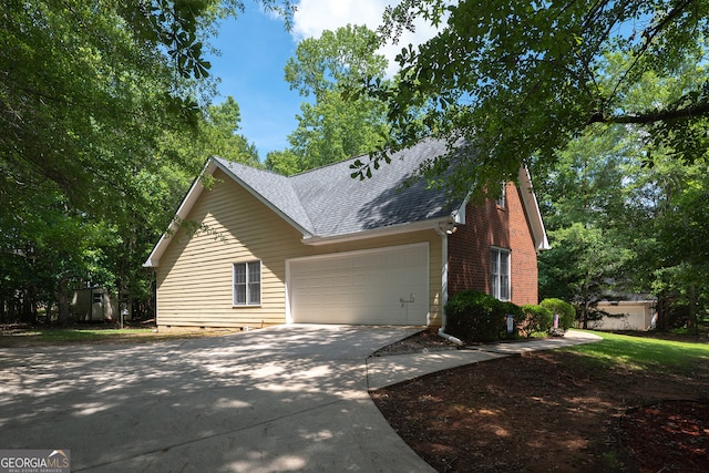 491 Brickleberry Rdg, Athens, GA 30605 - view of home's exterior with concrete driveway, roof with shingles, a garage, brick siding, and a storage shed