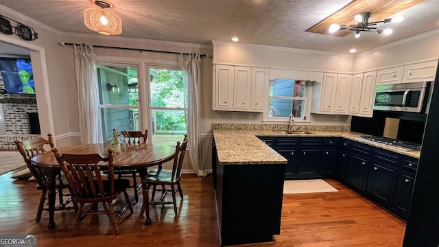 1310 Larkview Dr SW, Lilburn, GA 30047 - kitchen featuring stainless steel appliances, white cabinets, light wood-style floors, ornamental molding, and light stone counters
