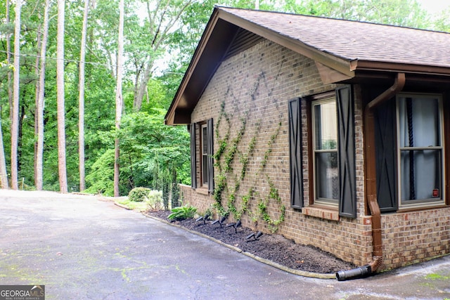 1310 Larkview Dr SW, Lilburn, GA 30047 - view of side of property with brick siding, a shingled roof, and a forest view