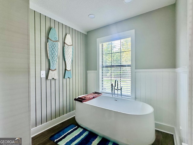 226 Cherokee Rd, Glenwood, GA 30428 - full bath featuring a freestanding tub, a wainscoted wall, a textured ceiling, and wood finished floors