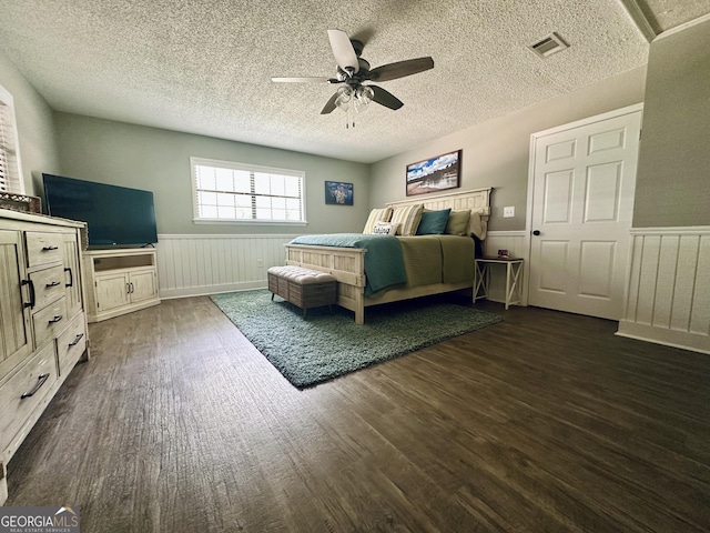 226 Cherokee Rd, Glenwood, GA 30428 - bedroom with dark wood finished floors, a wainscoted wall, a textured ceiling, and a ceiling fan