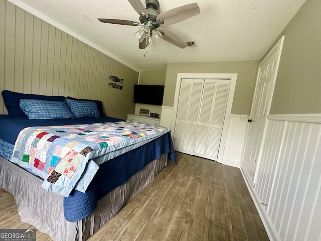 226 Cherokee Rd, Glenwood, GA 30428 - bedroom featuring wood finished floors, a closet, a textured ceiling, a ceiling fan, and a wainscoted wall