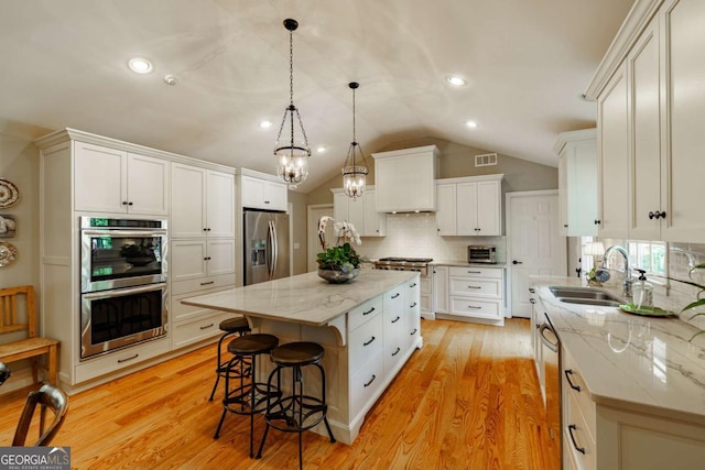 1060 Woodhollow Ln, Athens, GA 30606 - kitchen with stainless steel appliances, vaulted ceiling, decorative backsplash, light wood-type flooring, and white cabinets