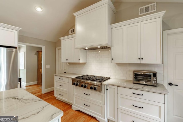 1060 Woodhollow Ln, Athens, GA 30606 - kitchen featuring stainless steel gas stovetop, refrigerator, lofted ceiling, tasteful backsplash, and white cabinetry