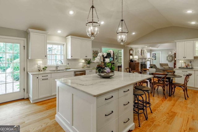 1060 Woodhollow Ln, Athens, GA 30606 - kitchen with a kitchen island, backsplash, light wood-style flooring, white cabinetry, and a kitchen breakfast bar