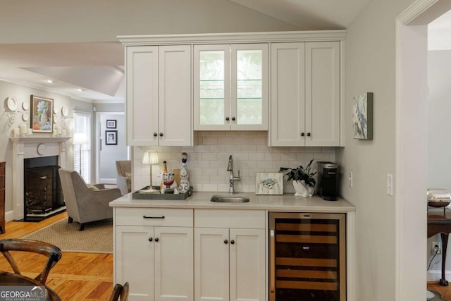1060 Woodhollow Ln, Athens, GA 30606 - indoor wet bar featuring wine cooler, light wood-type flooring, decorative backsplash, a fireplace, and ornamental molding
