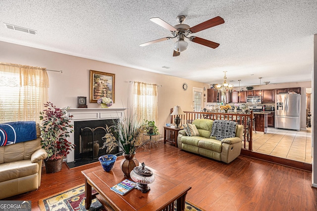 11961 Markham Way, Hampton, GA 30228 - living area with ceiling fan, light wood-style flooring, a chandelier, a textured ceiling, and a fireplace with raised hearth
