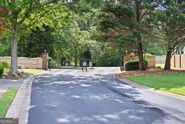 5069 Kathryn Glen Dr, Acworth, GA 30101 - view of asphalt road featuring curbs, a gate, traffic signs, and a gated entry