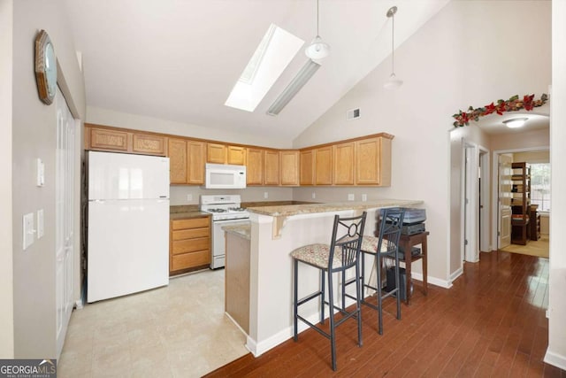 5069 Kathryn Glen Dr, Acworth, GA 30101 - kitchen featuring white appliances, a skylight, a peninsula, a kitchen bar, and decorative light fixtures