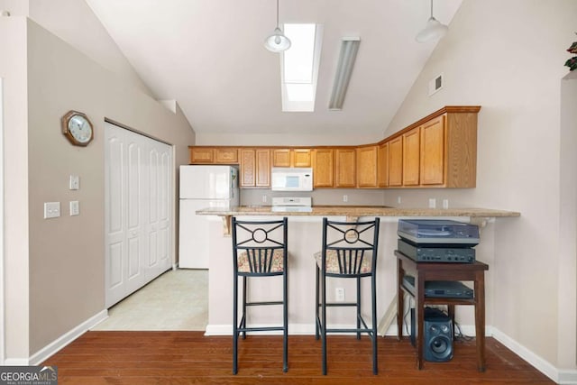 5069 Kathryn Glen Dr, Acworth, GA 30101 - kitchen featuring white appliances, lofted ceiling, light wood finished floors, a peninsula, and a kitchen breakfast bar
