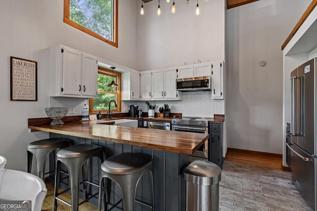 128 Overlake Ct, Morganton, GA 30560 - kitchen with wooden counters, appliances with stainless steel finishes, a towering ceiling, white cabinetry, and a peninsula