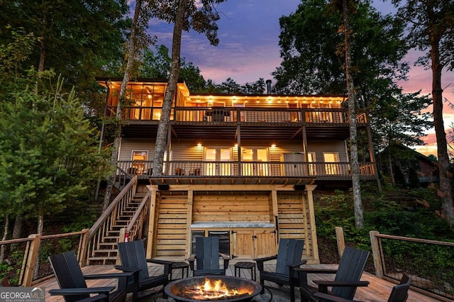 128 Overlake Ct, Morganton, GA 30560 - back of property at dusk with a fire pit, a jacuzzi, stairs, a deck, and a patio area
